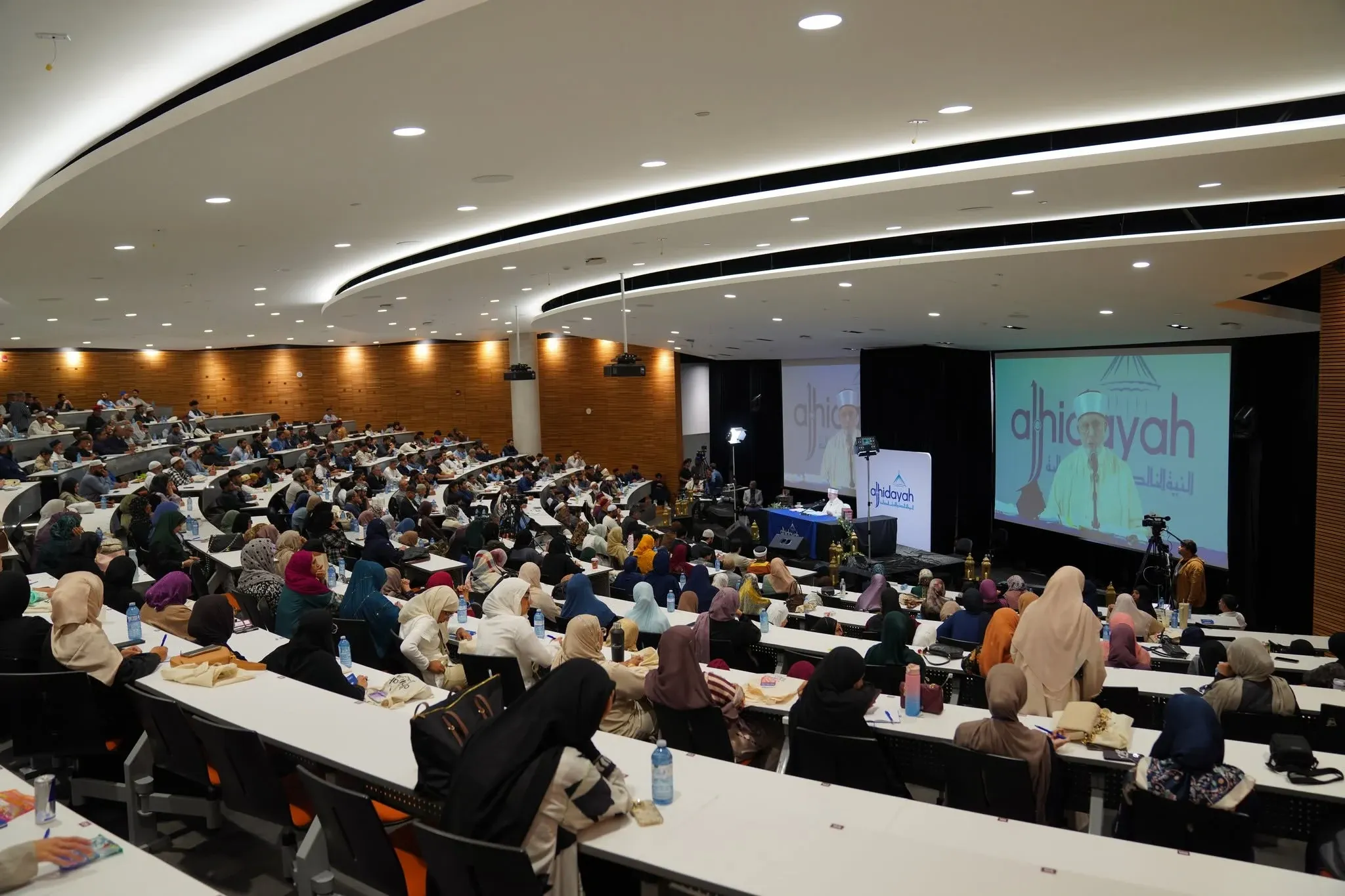 A speaker addressing a full Al-Hidayah Canada auditorium